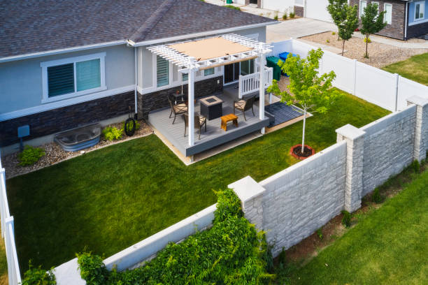 a backyard of a suburban usa home with a deck and pergola, aerial view.